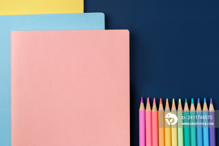 top view pastel notebook with pencil and stationery on navy blue table background