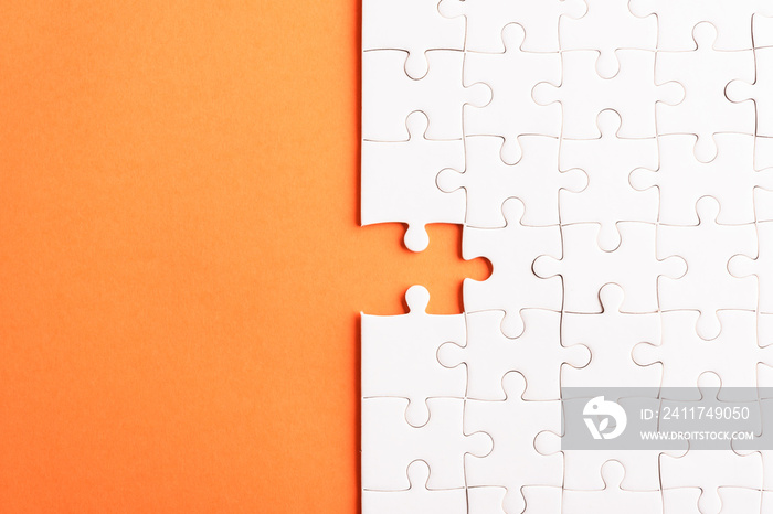 Top view flat lay of paper plain white jigsaw puzzle game texture last pieces for solve and place, studio shot on an orange background, quiz calculation concept