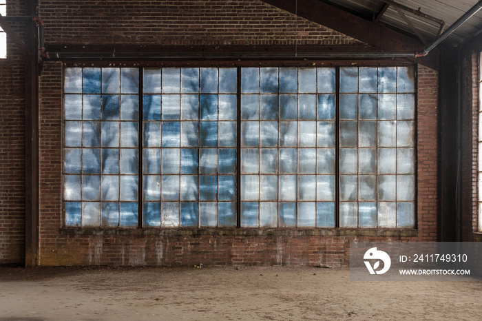 Large blue frosted windows in a loft like space of an abandoned factory with brick walls