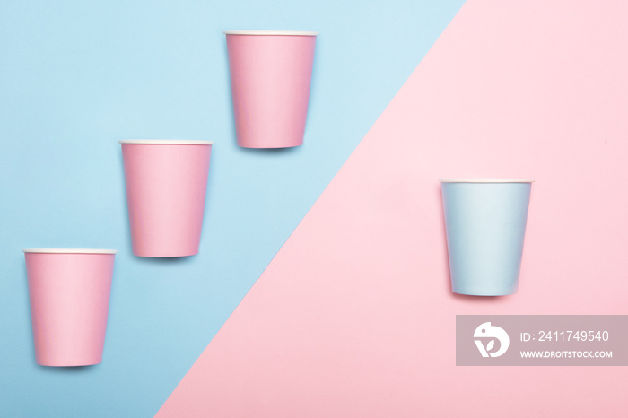 Mint blue and pink paper drinking cups on duotone pink and blue background. Birthday party celebration abstract fashion baby shower concept. Minimalist pastel style.