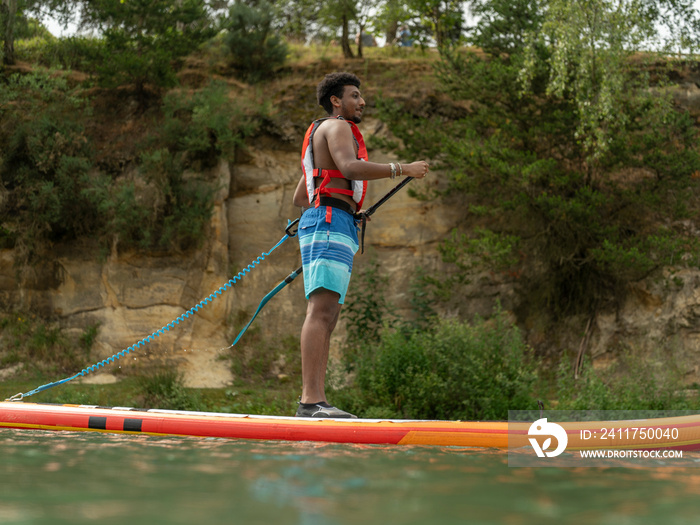 Young man paddleboarding on lake