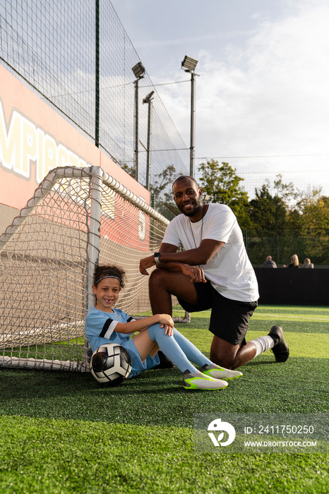 Portrait of coach and girl (6-7) by soccer goal