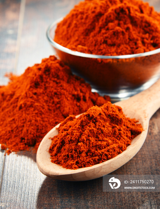 Composition with bowl of chili powder on wooden table