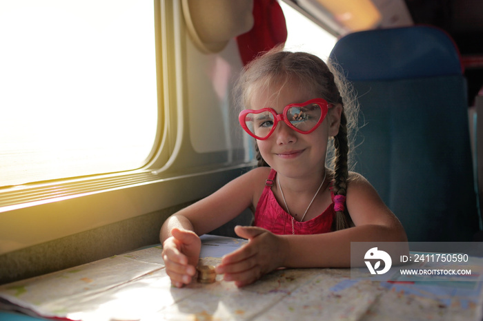 Little girl with planning her economy vacation during travelling by train