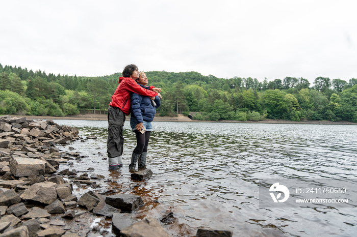 Mother and son wading in lake and hugging