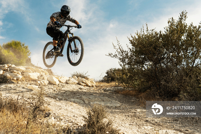 Professional bike rider jumping during downhill ride on his bicycle