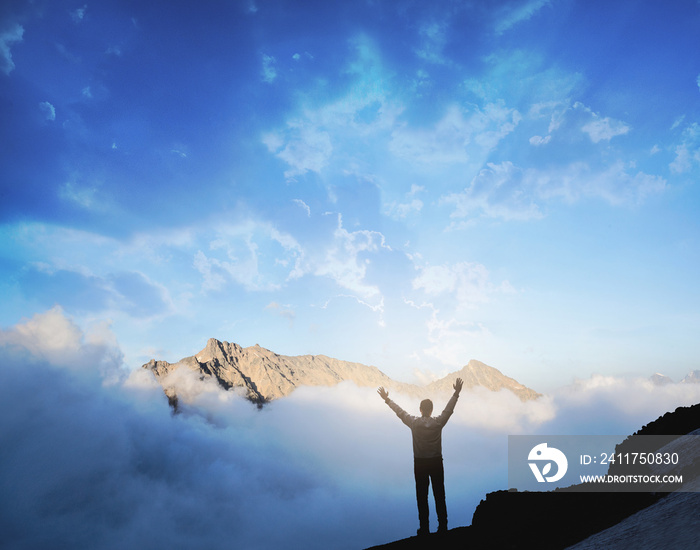 Man raises hands standing on the top of mountain. Victory and sucsess