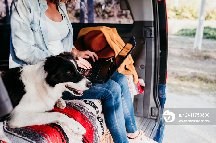 woman and border collie dog in a van. woman working on laptop. Travel concept