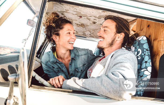Hipster couple driving at roadtrip on oldtimer mini van transport - Travel lifestyle concept with indie people having fun in relax moment on minivan adventure trip - Warm bright filter