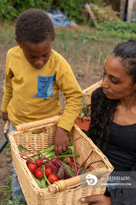 Mother and son holding basket with fresh vegetables