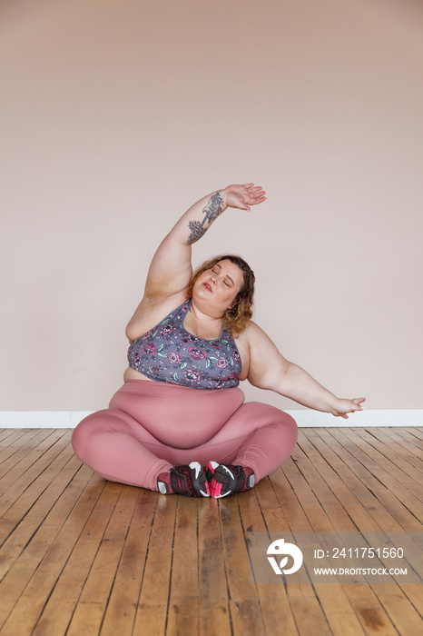 plus size woman sitting on floor stretching