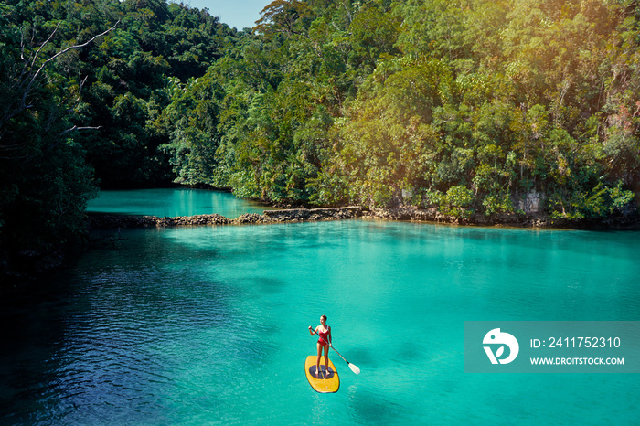 Summer holidays vacation travel. SUP Stand up paddle board. Young woman sailing on beautiful calm lagoon.