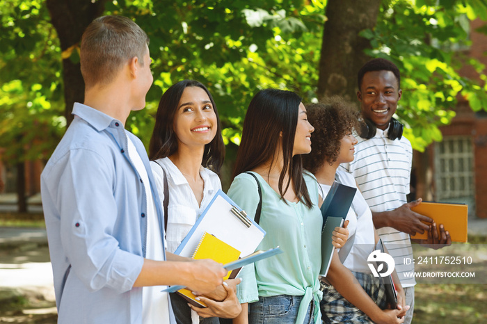 Cheerful University Friends Chatting After Classes While Walking Outdoor Together