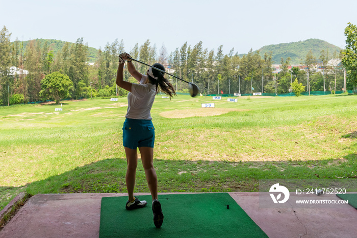 Asian golfer woman swing golf ball practice at golf driving range for relax and healthy care port. Lifestyle and Sport Concept