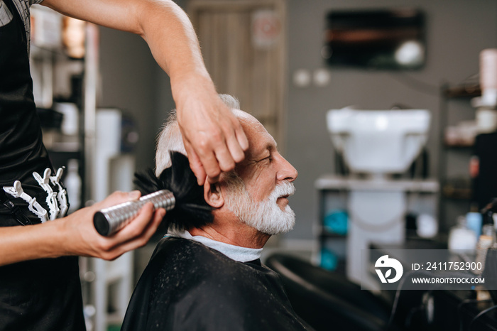 Senior good looking gettingt haircut in a hairdresser’s salon.