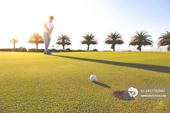 Golf club and ball in grass at the Golf course. White Golf ball on Green field golf course in morning time with sun light. Professional golf player fell Excited putting golf ball on green