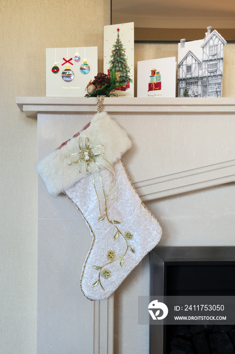 white christmas stocking hanging from mantle piece with cards on display