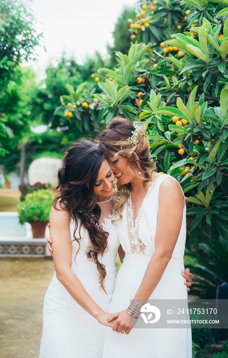 Portrait of a proud couple kissing each other with white wedding dresses