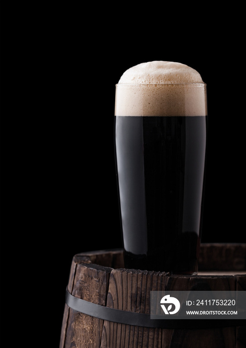 Cold glass of dark stout beer on wooden barrel