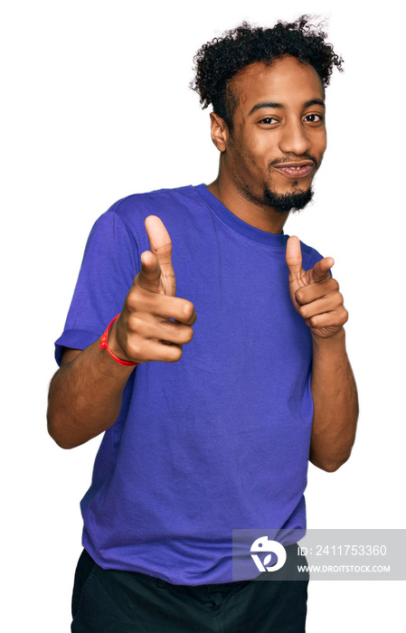 Young african american man with beard wearing casual purple t shirt pointing fingers to camera with happy and funny face. good energy and vibes.