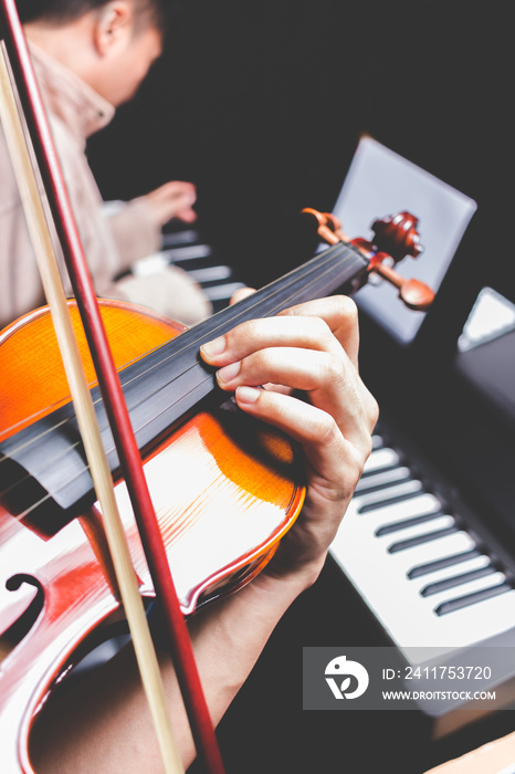 musician hands playing violin on pianist playing piano background, music concept