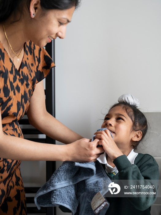 Mother helping son (6-7) dry face with towel