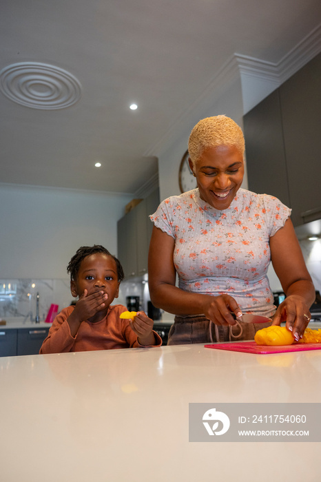 Mother and daughter (2-3) preparing food in kitchen