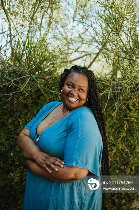 portrait of a plus size African American woman standing in front of plants looking away