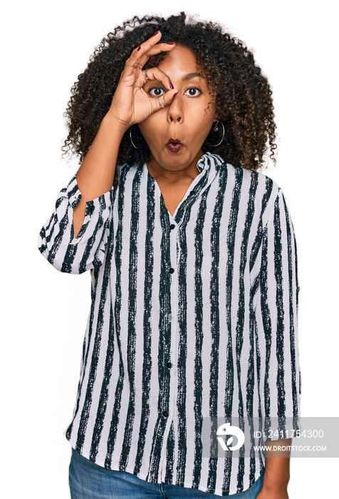 Young african american girl wearing casual clothes doing ok gesture shocked with surprised face, eye looking through fingers. unbelieving expression.