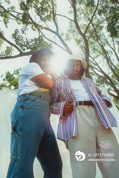 Malaysian Indian men in a group against a cloth backdrop in a park surrounded by trees, talking, laughing and sitting together