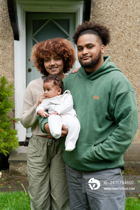 Parents holding baby daughter in front of home