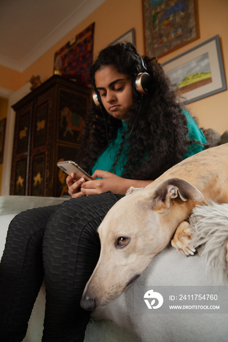 Curvy Indian girl with Cerebral Palsy playing on her phone next to her pet dog