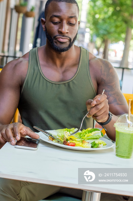 Mid adult man eating salad in cafe