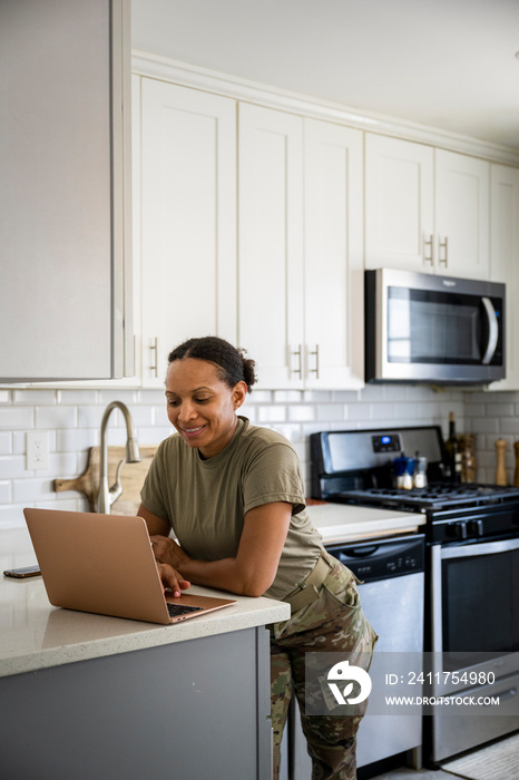 U.S. Army female soldier on her computer in her kitchen