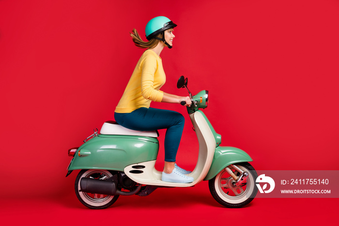 Profile side view of her she nice attractive lovely cheerful cheery girl driving moped to college high school motion adventure isolated on bright vivid shine vibrant red color background