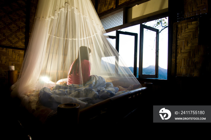 beautiful woman Sit and watch the morning scenery, Inside the mosquito net, To prevent mosquitoes.