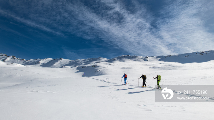 Three friends during a ski mountaineering trip on the trail