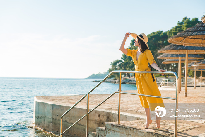 young pretty woman in yellow sundress at sea beach