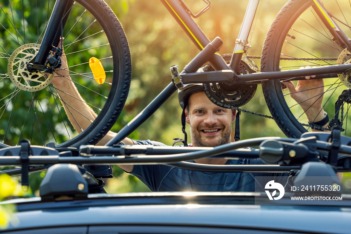 smiling cyclist mounting his bike on the car roof rack