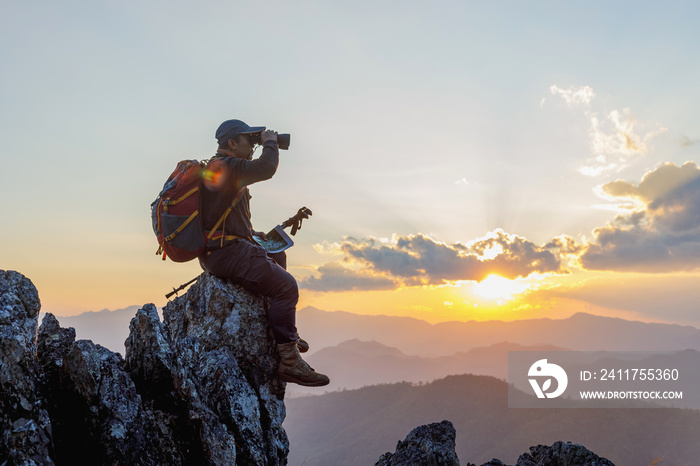 Hikers with backpacks holding binoculars sitting on top of the rock mountain