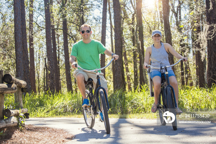 Happy attractive couple on a bike ride together outdoors on a bicycle path in the woods. Bike rental photo