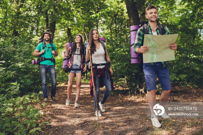 Four best friends are walking in autumn  forest, amazed by the beauty of nature, wearing comfortable outfits for hiking, sneakers, hats, have backpacks