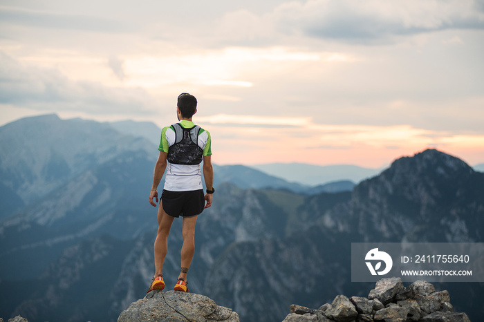 man standing on top of a mountain with a backpack on his back and a sunset in the background behind him - Landscape nature concept