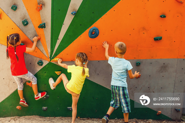 Two little girls boy climbing a rock wall