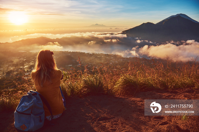 Woman enjoying nice landscape and sunrise from a top of mountain Batur, Bali, Indonesia.