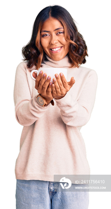 Young beautiful mixed race woman holding a cup of coffee looking positive and happy standing and smiling with a confident smile showing teeth