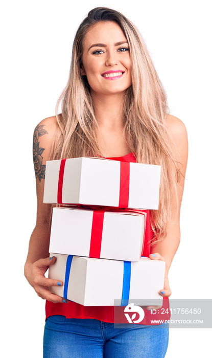 Young beautiful blonde woman holding birthday gifts looking positive and happy standing and smiling with a confident smile showing teeth