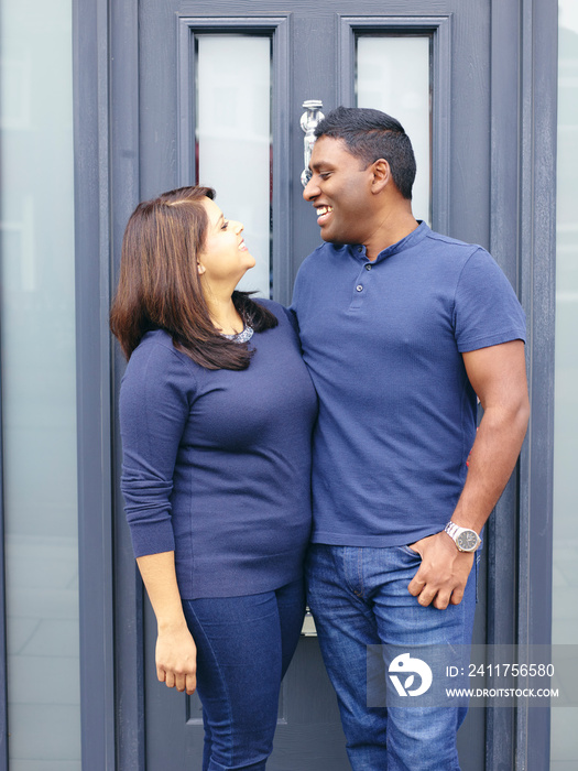 Smiling couple standing at front door