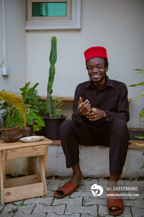 an igbo man sitting outside his house