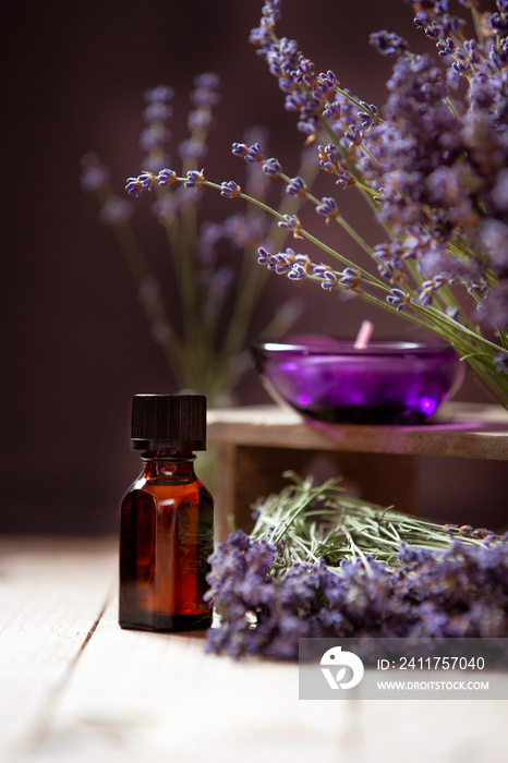 Herbal oil and lavender flowers on wooden background